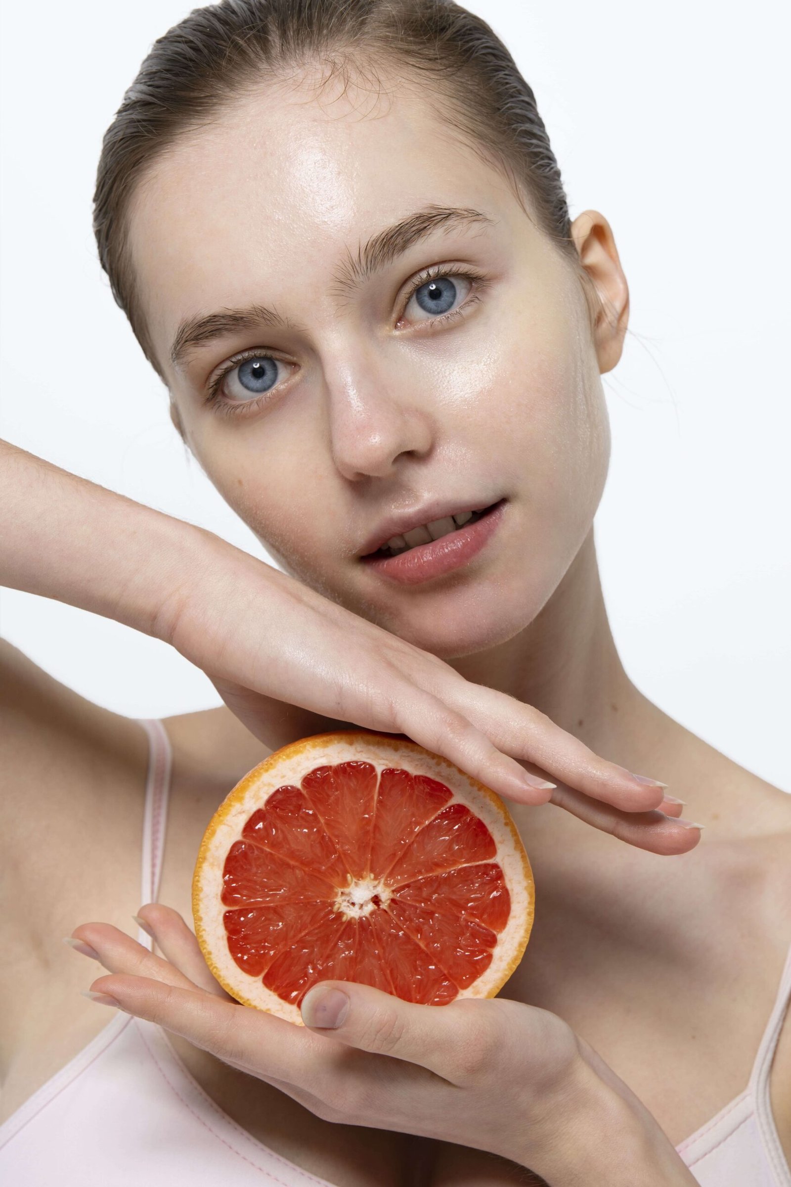 Woman with glowing skin holding grapefruit representing skin glow and hydration
